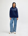 A navy blue Gildan Heavy Blend adult hooded sweatshirt worn by a model with jeans and sneakers. The sweatshirt features a hood and pockets.