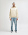 A light beige hooded sweatshirt worn with blue jeans, featuring a front pocket and a drawstring hood.