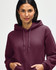 A hooded sweatshirt in a deep burgundy colour, featuring a drawstring hood and an individual adjusting the neckline.