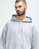 A grey Gildan Heavy Blend adult hooded sweatshirt on a male model, featuring a drawstring hood and a logo.
