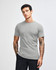 A grey unisex short sleeve T-shirt displayed on a model with hands in pockets, featuring a simple design.