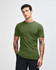 A unisex fine jersey short sleeve t-shirt in a rich green colour, displayed on a model with hands in pockets.