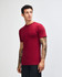 A maroon unisex short sleeve t-shirt displayed on a model, featuring a logo.