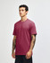 A maroon unisex CVC short sleeve T-shirt displayed on a model with tattoos. The shirt features a logo.