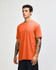 An orange unisex CVC short sleeve t-shirt displayed on a model, featuring a casual fit and a logo.
