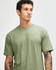 A green unisex CVC short sleeve T-shirt is displayed on a model with a neutral background. It features a logo.