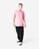 A model wearing a pink unisex CVC short sleeve t-shirt paired with dark cargo pants and trainers.