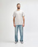 A grey Gildan Heavy Cotton adult T-shirt displayed on a person, paired with light blue jeans and black shoes.
