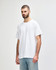 A white Gildan Heavy Cotton adult T-shirt displayed on a model with dark jeans. The shirt features a logo.