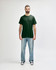 A green Gildan Heavy Cotton adult T-shirt displayed on a male model, paired with black jeans and sneakers.
