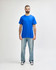 A man stands wearing a blue Gildan Heavy Cotton Adult T-Shirt paired with light blue jeans.