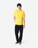 A yellow Gildan Heavy Cotton adult T-shirt worn by a male model, alongside black pants and sneakers.