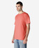 A model wearing a coral Gildan Heavy Cotton Adult T-Shirt, paired with light blue jeans. The shirt has a logo.