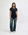 A black ladies' t-shirt displayed on a model, paired with blue jeans and white shoes, featuring a logo.