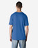 A blue Gildan Softstyle adult T-shirt viewed from the back, featuring a plain design and a tag.