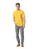 A man wearing a bright yellow Gildan Softstyle adult T-shirt and grey jeans, standing casually.
