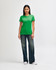 A green Gildan Softstyle ladies' t-shirt paired with blue jeans and white sneakers, modelled by a woman.