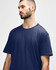 A model wearing a navy blue Gildan Softstyle Adult Midweight T-Shirt. The shirt has a round neckline and short sleeves.