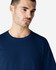 A model wearing a navy blue Gildan Softstyle Adult Midweight T-Shirt. The shirt has a round neckline and short sleeves.