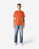 An orange Gildan Softstyle adult midweight T-shirt worn by a model with denim jeans and white shoes.