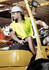 A man wearing a yellow and navy hi-vis short sleeve polo shirt operates a forklift, wearing a safety helmet.