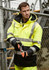 A man's high-visibility waterproof jacket in yellow and black with reflective strips, worn with gloves.