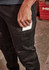 A close-up of a person wearing black stretch jeans, with a hand reaching into a side pocket holding a white item.