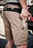 Men's beige work shorts with multiple pockets, featuring a tool in one pocket and a logo on the waistband.