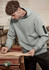 A light blue unisex multi-pocket hoodie worn by a man working in a workshop, featuring a logo on the sleeve.