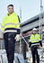 A high visibility yellow hoodie with black stripes, worn by two men on a construction site, featuring a logo.