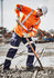An orange long sleeve work shirt with reflective stripes, worn by a worker using a shovel in a construction environment.