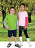 A green and grey long-sleeve t-shirt worn by a boy, and a pink and grey long-sleeve t-shirt worn by a girl, set in a grassy landscape.