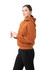 A woman wearing an orange kangaroo pocket hoodie, featuring a hood and a relaxed fit, paired with black pants.