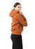 A woman smiles while wearing a burnt orange cotton hoodie with a kangaroo pocket and a logo.