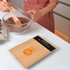 A bamboo kitchen scale with a digital display sits on a countertop beside a mixing bowl filled with ingredients.