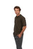 A man models a brown pigment dyed polo shirt, featuring a classic collar and short sleeves, with branding present.