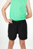 Kids' FLEX shorts in black, featuring a comfortable elastic waistband and 4-way stretch design, paired with a green top.
