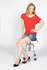 A model poses on a stool wearing a red bat wing T-shirt, denim shorts, and black high heels. The image includes a branding logo.