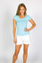 A light blue women's cotton/spandex t-shirt modeled by a smiling woman, paired with white shorts. The shirt has a logo.