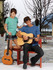 A blue and a green heavy marl T-shirt displayed on a man playing guitar and a woman standing nearby with a guitar.