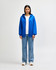 A blue Gildan Heavy Blend adult full zip hooded sweatshirt on a model, paired with light jeans and white shoes.