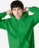 A green full zip hooded sweatshirt with a hood, worn by a model adjusting it. The sweatshirt features a logo.