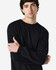 A model wearing a long sleeve t-shirt in black, featuring a logo on the sleeve.