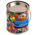 A clear PVC bucket filled with colourful choc beans, featuring a metal lid and a handle. Includes branding on the front.