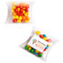 A clear pillow pack containing chewy fruit candies in red, yellow, and blue colours, with a logo present.