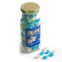 A tall glass jar filled with blue and white mini jelly beans, with a gold lid and a logo on the front.