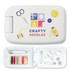 A white sewing kit with colorful graphics, containing threads, needles, buttons, scissors, and safety pins.