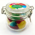 A small glass canister filled with colourful Christmas mixed lollies in red, green, yellow, and blue.
