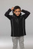 A black children's jacket with a hood, featuring reflective trim, worn by a child. It has a logo on the chest.
