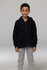 A child stands wearing a black zip-up hoodie and grey pants, featuring a hood and front pockets.